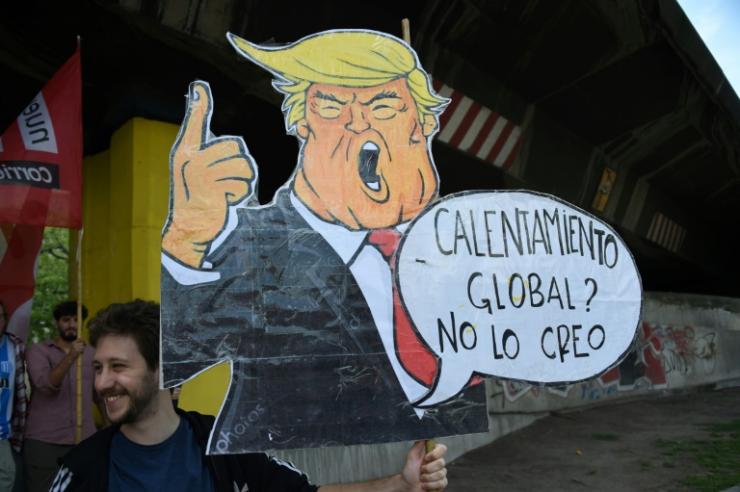Un homme porte une caricature de Donald Trump disant "Réchauffement global? Je n'y crois pas", le 30 novembre 2018 à Buenos Aires. Le climatoscepticisme du président américain est un modèle pour les certaines Européens  © AFP/Archives MARTIN BERNETTI