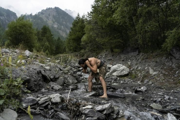 Un homme habillé comme un homme de Neanderthal se lave dans une rivière des Alpes italiennes  © AFP/Archives MARCO BERTORELLO