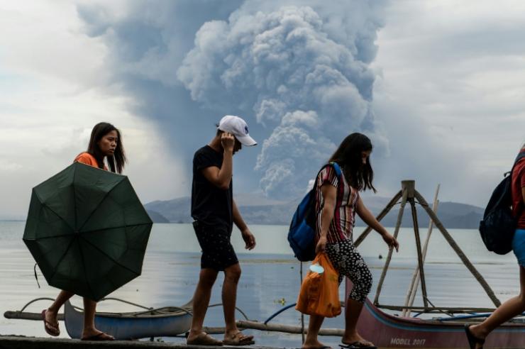 Des habitants longent des barques devant le volcan Taal en éruption aux Philippines, à 65 km de Manille, le 13 janvier 2020 © AFP Ted ALJIBE