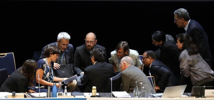 Les coprésidents du groupe scientifique et les membres du support technique s'entretiennent avec les auteurs principaux, en septembre 2019 à Monaco lors de l'approbation du rapport spécial sur les océans et la cryosphère.