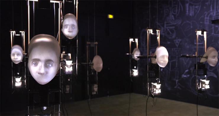 Œuvre de Zaven Paré. Chœur d'enfants aux visages rétro-projetés murmurant un opéra de Kurt Weill  lors de l’exposition « Mécatronic » au Centre d’art d’Enghien-les-Bains en 2016 