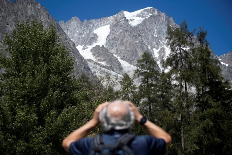 Un homme observe avec des jumelles le glacier de Planpincieux à Courmayeur, le 6 août 2020 au Val Ferret, en Italie © AFP Marco Bertorello