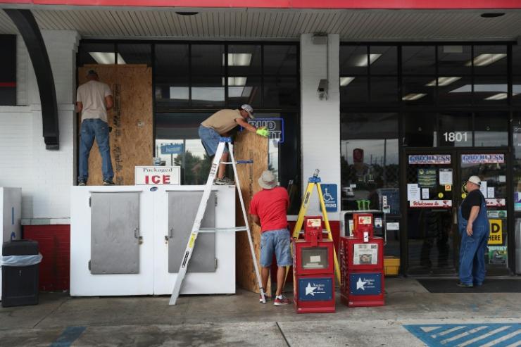 Des employés installent des panneaux en bois pour protéger les vitrines d'une boutique avant l'arrivée de l'ouragan Laura, le 25 août 2020 à Lake Charles en Louisiane 
