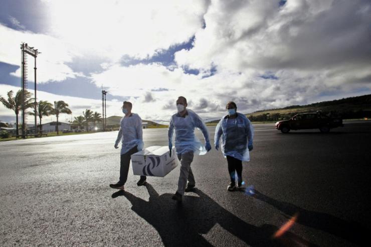 Des travailleurs débarquant les caisses contenant environ 1.200 doses du vaccin Sinovac à l'aéroport international de l'Ile de Pâques le 4 février 2021 