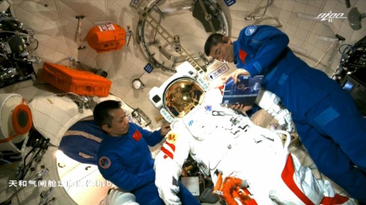 Les astronautes chinois Tang Hongbo (G) et Liu Boming (D) le 23 juin 2021 à bord de la station spatiale Tiangong, avec la combinaison qu'ils ont utilisée le 4 juillet pour sortir dans l'espace © CCTV/AFP