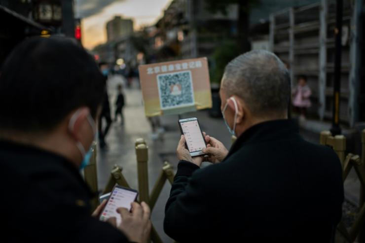 Dans les rues de Pékin, des habitants scannent leur QR code pour pénétrer dans un quartier de la ville, le 13 octobre 2020 © AFP/Archives NICOLAS ASFOURI