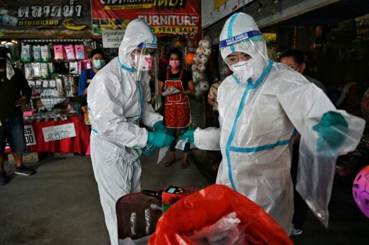 Des chercheurs de l'université Chulalongkorn en combinaison de protection prélèvent des échantillons de sueur sur des vendeurs d'un marché de Bangkok, le 8 septembre 2021 en Thaïlande © AFP Lillian Suwanrumpha