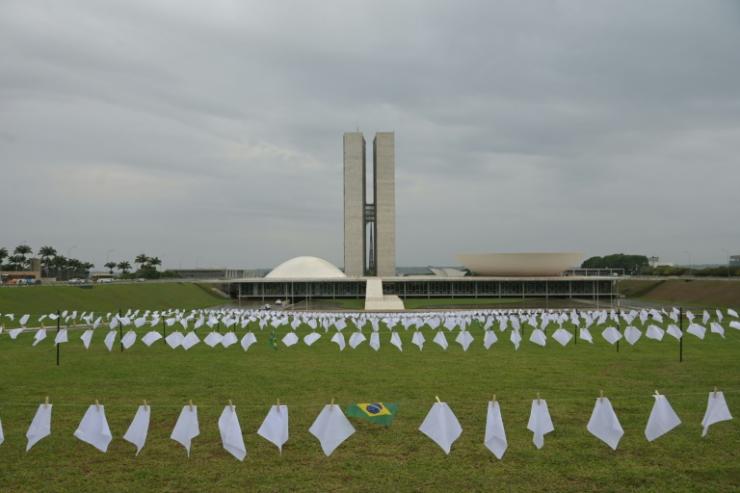 Des militants accrochent des mouchoirs blance en hommage aux morts du Covid, devant le Congrès national du Brésil, à Brasilia, le 18 octobre 2021. © AFP EVARISTO SA