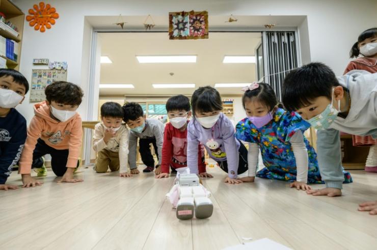 Des élèves d'une école maternelle observe le robot "Alpha Mini", le 23 novembre 2021 à Séoul, en Corée du Sud © AFP Anthony WALLACE