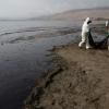 Des équipes de nettoyage ramassent le pétrole d'une plage près de la station balnéaire d'Ancon, à Lima, au Pérou, le 20 janvier 2022 © AFP Cris BOURONCLE