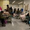 lits d'hôpitaux dans une entrée, patients asiatiques avec masques, écritaux en mandarin